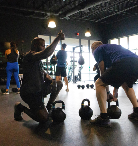 A group of people in the gym with kettlebells.